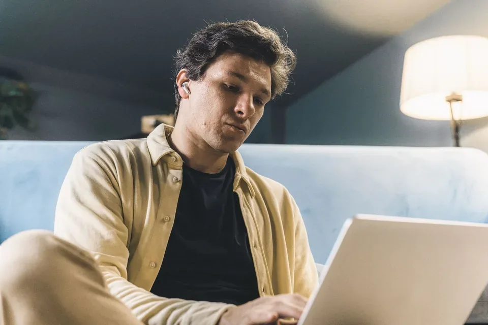 Férfi este a kanapén dolgozik a laptopján